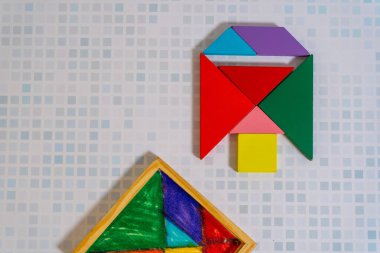 Renkli bir Tangram yapbozu ahşap bir masa üzerinde kabıyla bir figür oluşturuyor..