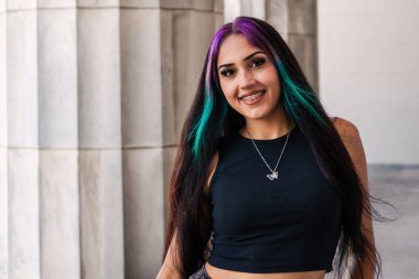 Geniş bir klasik binanın sütunları arasında genç bir kadının portresi.