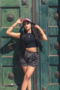 Genç bir kadın büyük eski bir kapıya yaslanıyor..