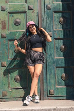 Genç bir kadın büyük eski bir kapıya yaslanıyor..