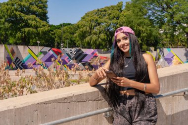 Gülümseyen bir milenyum kadını cep telefonu mesajlarını kontrol ediyor.