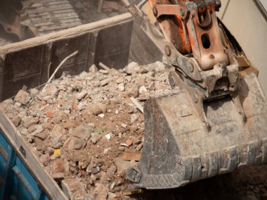 Kazıcı yıkım alanından enkazı kaldırıyor ve boşaltıyor..