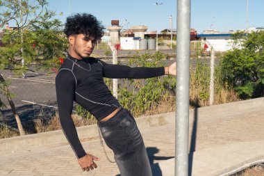 Sokakta bir köşe yazısına tutunarak ciddi bir ifade takınan Latin kökenli genç bir Afrikalı.