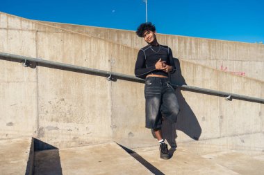 Büyük beton bir merdivende poz veren neşeli ve dostane bir ifadeyle genç bir İspanyol Afrikalı.