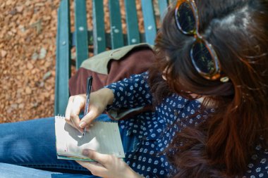 Yazar park bankında otururken not alıyor. Eller 'e odaklan