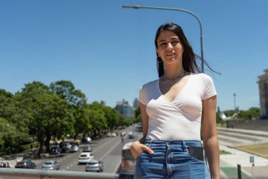 Buenos Aires, Arjantin 'de bir köprüde duran şık genç kadın şehir manzarasının tadını çıkarıyor.