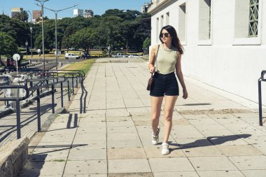 Buenos Aires, Arjantin 'de kaldırımda yürüyen şık bir kadın güneşli bir günün tadını çıkarıyor.