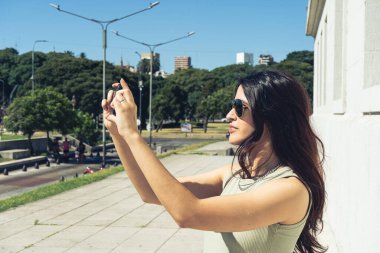 Buenos Aires 'te bir parkta telefonuyla fotoğraf çeken genç bir turist.