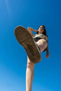 Zarif Latin bir kadının mavi gökyüzüne doğru bir adım attığı düşük açılı bakış açısı