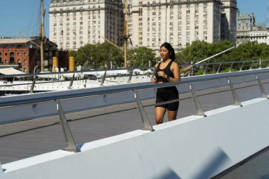 Genç sporcu dışarıda antrenman yaparken Puerto Madero, Buenos Aires 'te bir köprüde koşuyor.