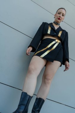 Mini etekli, siyah ve altın rengi bir elbise giyen genç bir kadın.