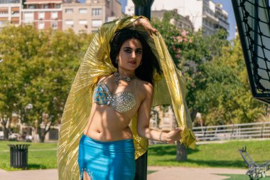 Gökyüzü mavisi ve altın ipekli dansçı boş bir parkta