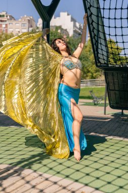 Rüzgarda altın eşarbı olan mavi elbiseli bir Arap dansçı.