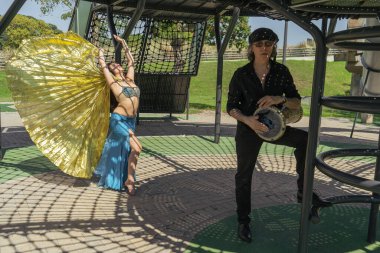 Bir Odalisque ve darbuka oyuncusu gündoğumunda enerji ve ritim dolu