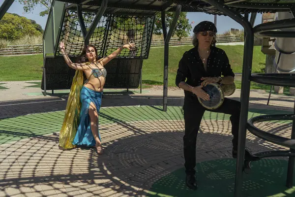 Odalisque ve darbuka oyuncusu Güneşin altındaki rüya gibi bir bahçede