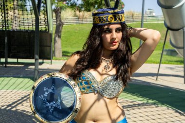 Gölgelerde Darbuka olan mavi elbiseli bir Arap dansçı.