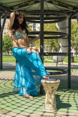 Gölgelerde Darbuka olan mavi elbiseli bir Arap dansçı.