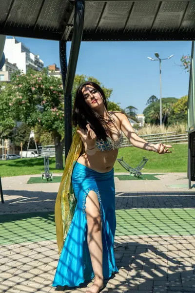 Rüzgarda altın eşarbı olan mavi elbiseli bir Arap dansçı.