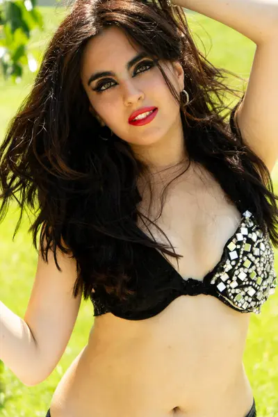 Parkta gümüş ve ayna detaylarıyla siyah elbiseli bir Arap dansçı.