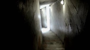 Işık, dar bir taş merdivenin bölümlerini aydınlatır. Karanlık, muhtemelen antik bir yapıdan geçer.