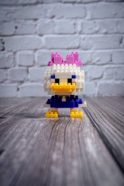 Küçük papatya ördeği nanoblock figürü tahta yüzeyde duruyor.