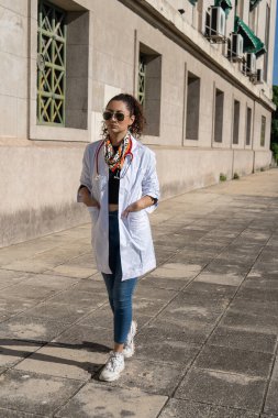 Laboratuvar önlüğü, steteskop ve güneş gözlüğü takan kendine güvenen bir doktor.