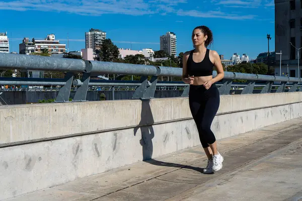 Kentsel çevrede koşan sağlıklı bir kadın sağlıklı yaşam tarzı ve kondisyonunu destekliyor.