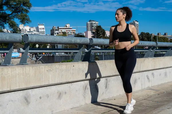 Kentsel çevrede koşan sağlıklı bir kadın sağlıklı yaşam tarzı ve kondisyonunu destekliyor.