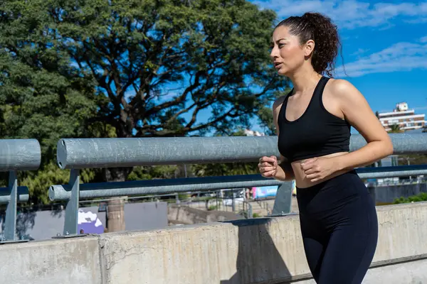 Kentsel çevrede koşan sağlıklı bir kadın sağlıklı yaşam tarzı ve kondisyonunu destekliyor.