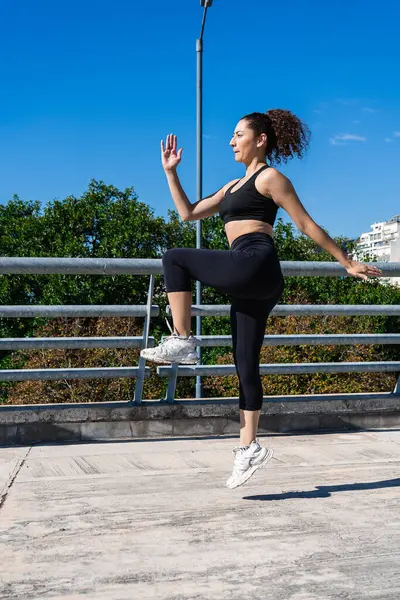 Açık havada egzersiz yaparken dizlerini çalıştıran sağlıklı bir kadın.