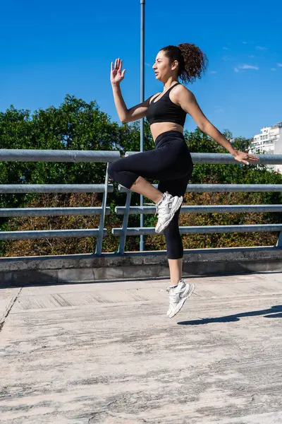 Açık havada egzersiz yaparken dizlerini çalıştıran sağlıklı bir kadın.