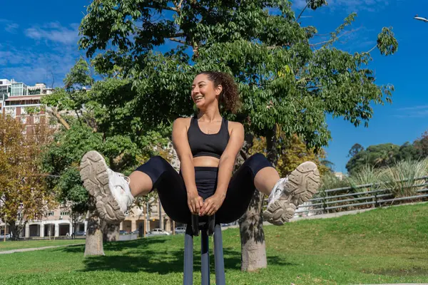 Parktaki spor aletlerini kullanarak karın kaslarını güçlendiriyor.