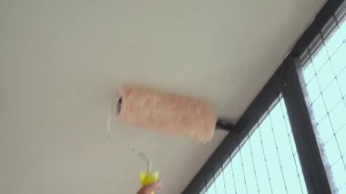 Boyacı boya silindiri kullanıyor, konut binasının ön cephesini boyuyor.