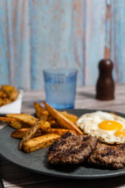 Kızarmış yumurta ve kızarmış patatesle servis edilen iki lezzetli ev yapımı hamburger doyurucu ve doyurucu bir yemek oluşturur.