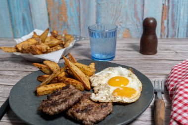 Kızarmış yumurta ve kızarmış patatesle servis edilen iki lezzetli ev yapımı hamburger doyurucu ve doyurucu bir yemek oluşturur.