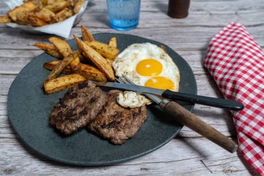 Kızarmış yumurta ve kızarmış patatesle servis edilen iki lezzetli ev yapımı hamburger doyurucu ve doyurucu bir yemek oluşturur.