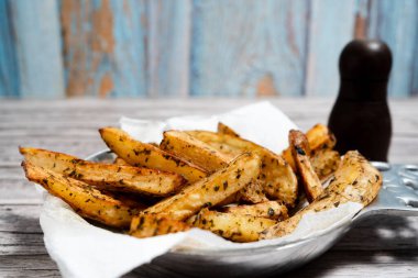 İştah açıcı, kavrulmuş, baharatlı ve otla tatlandırılmış patates dilimleri lezzetli ve görsel olarak çekici bir yemek yaratıyor.