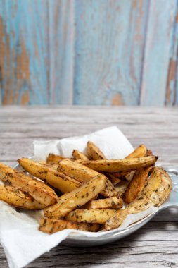 İştah açıcı, kavrulmuş, baharatlı ve otla tatlandırılmış patates dilimleri lezzetli ve görsel olarak çekici bir yemek yaratıyor.
