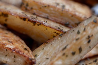 İştah açıcı, kavrulmuş, baharatlı ve otla tatlandırılmış patates dilimleri lezzetli ve görsel olarak çekici bir yemek yaratıyor.