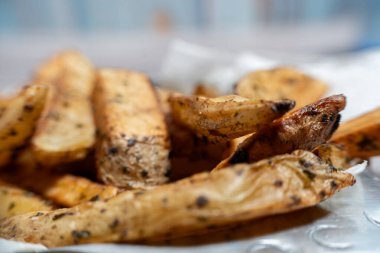 İştah açıcı, kavrulmuş, baharatlı ve otla tatlandırılmış patates dilimleri lezzetli ve görsel olarak çekici bir yemek yaratıyor.