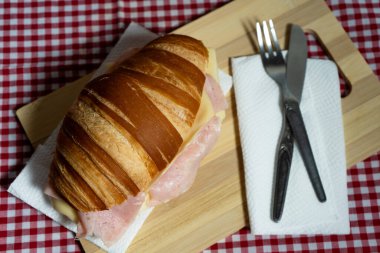 Lezzetli kruvasan sandviç sunumu. İçki ve çatal bıçak takımı. Kahvaltı masası için ayarlanmış..
