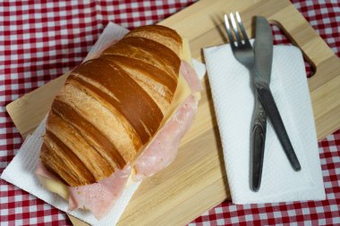 Dondurulmuş meyve suyu ve cilalanmış gümüşlerle birlikte Çin porselenlerinde sıcak kruvasan sandviçi sunan sofistike bir brunch sunumu..
