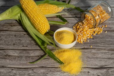 Koçanda taze mısır, çekirdekler ve mısır unu bu çok yönlü tahılın çeşitli formlarını gösteren, rustik ahşap bir masada sergilenir.
