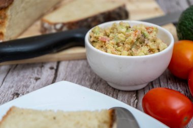 Ekmek ve taze domateslerle dolu bir kasede guacamole.