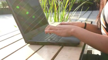 İş kadını dışarıda, tahta masada dizüstü bilgisayarda daktilo kullanıyor.