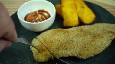 Aşçı ekmek arası pirzola ve ketçap kesip yiyor.