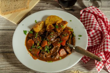 Köy ahşap bir masada otlarla süslenmiş tuzlu biftek güveci.