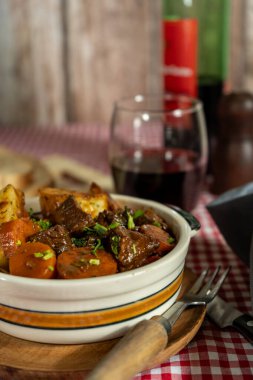 Havuç ve patatesle servis edilen lezzetli sığır güveci, kırmızı şarapla eşleştirilmiş.
