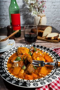 Koçanda mısır, sebze ve bir bardak kırmızı şarapla servis edilen tuzlu sığır güveci rahatlatıcı ve kırsal bir yemek deneyimi yaratıyor.