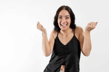 Neşeli genç kadın mutluluğunu ve heyecanını ifade ediyor. Zaferi ya da başarıyı kutluyor.